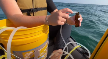 NOAA researcher Maddy Saddler collects water samples from Lake Huron to assess water chemistry and the carbon system as part of a 5 year project. Credit: TBNMS, September 2024